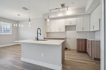 An open kitchen with a large white island and white cabinets